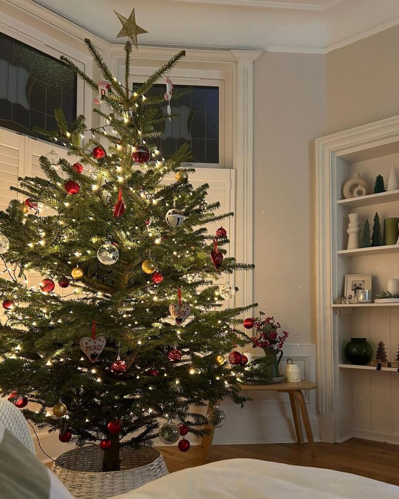 7ft Nordmann Fir Christmas tree with red and gold baubles in a woven basket stand